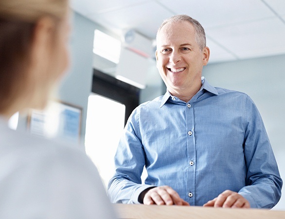 Older man smiling while checking in at reception desk