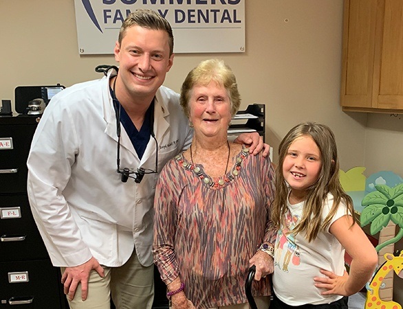 Dentist and two dental patients smiling together