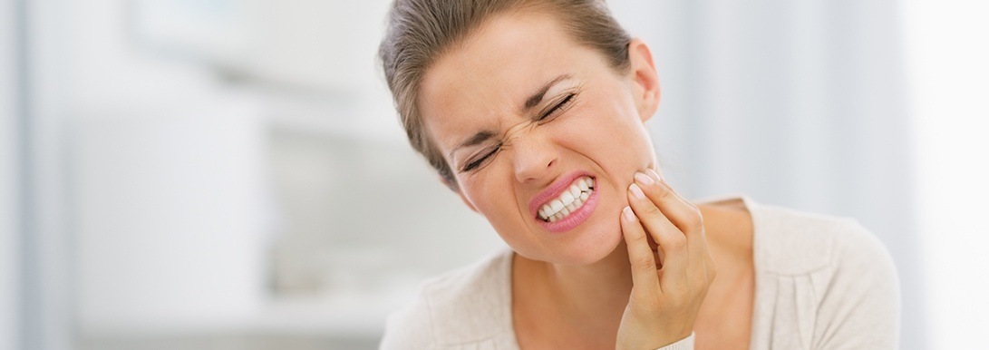 Woman holding jaw before emergency dentistry