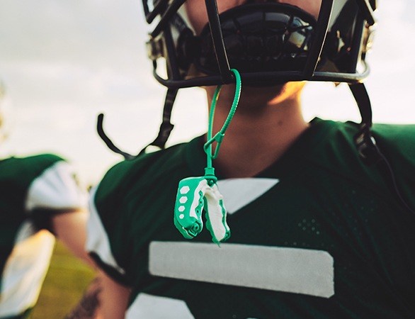 Teen boy with green athletic mouthguard on football helmet