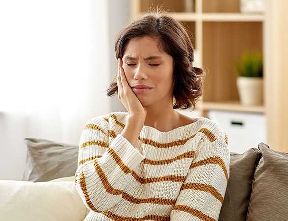 Woman in need of emergency dentistry holding cheek