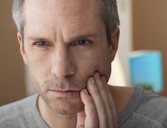 Man with broken tooth holding jaw