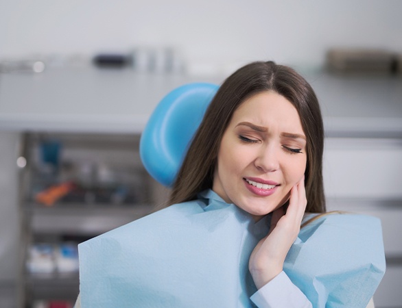 Woman with lost filling holding cheek at dental office