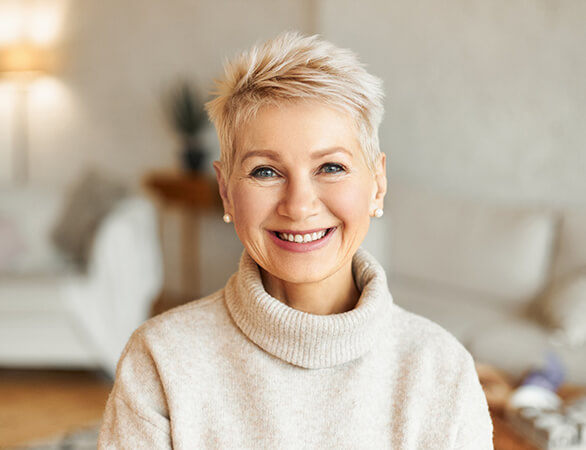 Senior woman wearing a sweater and showing natural-looking smile