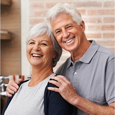 Older man and woman smiling after restorative dentistry