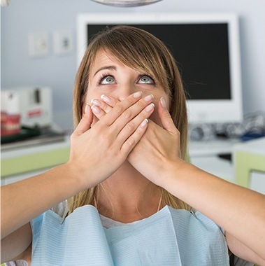 Woman in need of sedation dentistry covering her mouth