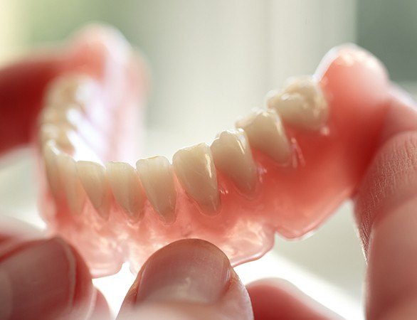 Hand holding a full denture