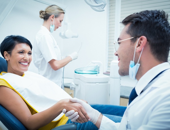 Dentist shaking hand with dental patient