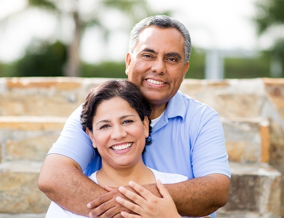 Older man and woman smiling together after pain relieving emergency dentistry