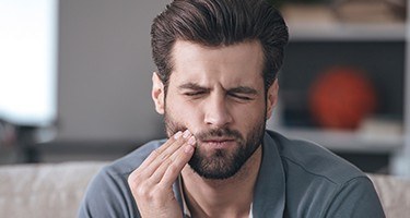 Man in need emergency dentistry holding cheek