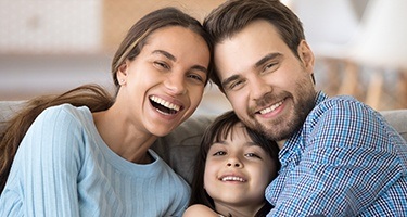Family of three smiling on couch