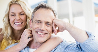Man and woman smiling and cuddling on couch