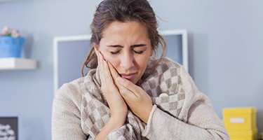 Woman holding her cheek in pain