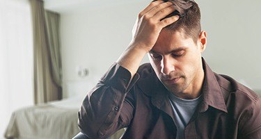 Man looking worried with his head in his hand