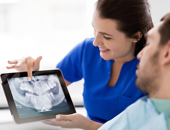 Dental team member and patient looking at periapical x-rays